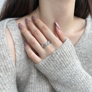 Detailed view of silver ring featuring light blue and white teardrop zircons on a model