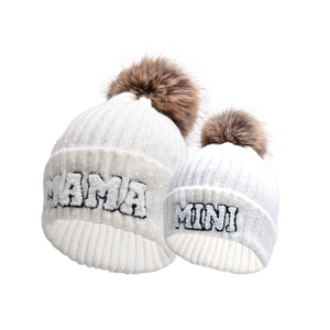 Dettaglio del set di cappelli in maglia crema con pompon e toppe MAMA e MINI