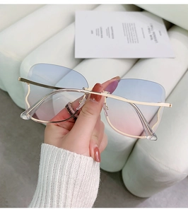 Detail of rimless butterfly sunglasses with blue to pink gradient lenses and gold arms