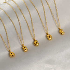 Detail showing golden bubble alphabet pendants A to E on elegant white silk background