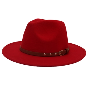 Macro detail of red fedora hat featuring a brown leather band and gold metal buckle