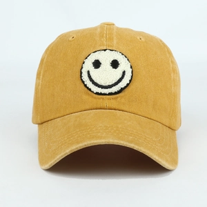 Detail of embroidered smiley face patch on mustard yellow washed cotton baseball cap