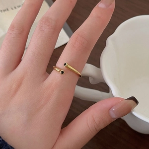 Close-up of golden 925 silver open ring with black stone accents on woman's hand