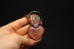 Macro detail of handmade heart-shaped rose quartz pendant with copper wire wrapping