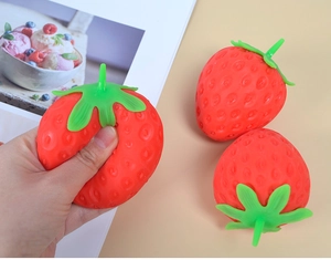 Detail of hand squeezing a realistic strawberry squishy toy for stress relief