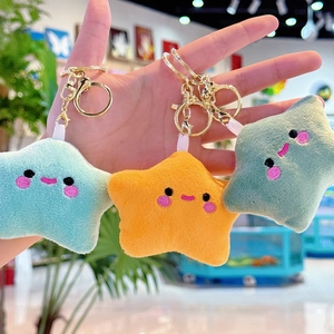 Macro view of plush star keychains with embroidered faces in blue yellow and green