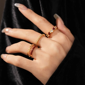 Macro shot of gold vintage rings with red enamel hearts and zircon stones on hand