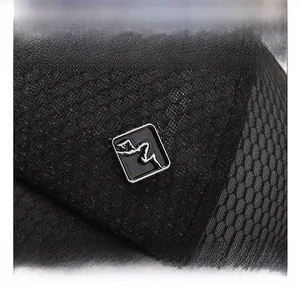 Close-up of black breathable mesh fabric and square mountain metal logo on baseball cap