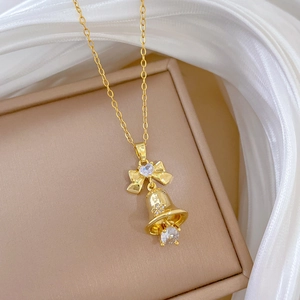 Close-up of golden bow and bell pendant with crystals on elegant silk fabric