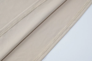 Détail macro du tissu en maille côtelée beige et couture plate sur la robe ajustée