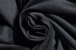 Macro detail of soft black milk silk fabric showing smooth texture and elastic drape