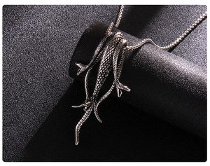Vue macro du pendentif lézard argenté montrant la texture des écailles sur une chaîne punk