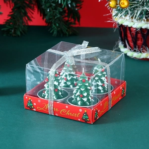 Detail of four green Christmas tree candles in a transparent gift box with silver ribbon