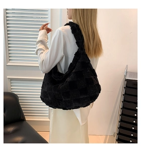 Detail of plush black checkered shoulder bag with soft textured surface on model