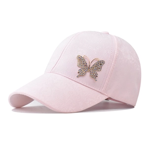 Detail of pink cotton baseball cap featuring embossed texture and rhinestone butterfly ornament