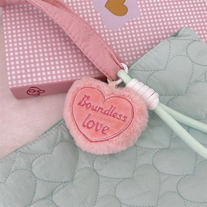 Detail of mint green quilted tote with heart pattern and pink plush heart charm