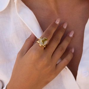 Close-up of a gold oval ring with star patterns and small zircon stones on a model's hand