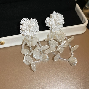 Detailed close-up of white floral tassel earrings with beaded texture and petals