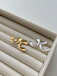 Polished gold and silver 925 sterling silver C-shaped geometric stud earrings on a beige tray