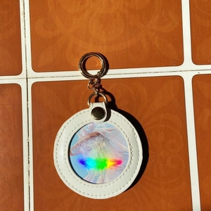 Witte lederen badge-sleutelhanger met gouden ring en holografisch anime-personage