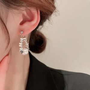 Detail of silver drop earrings with irregular geometric links and white hanging pearl