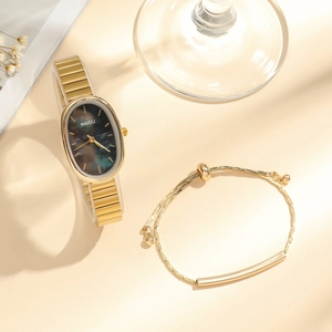 Detailed close-up of oval gold quartz watch and matching bracelet set on warm background