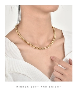 Detailed view of an 18K gold plated Cuban chain necklace with zircon stones on a model