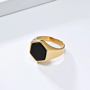 Minimalist gold titanium steel ring with a black hexagonal seal on a plain cold background