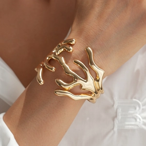 Detailed view of irregular golden coral-shaped cuff bracelet on a model's wrist