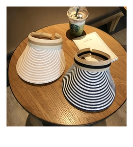 Detail of striped woven straw open-top sun hats in cream and navy for beach vacation