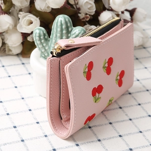 Close-up of pink leather wallet with cherry embroidery and golden zipper detail