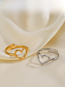 Detail of adjustable hollow heart rings in gold and silver finish on satin fabric