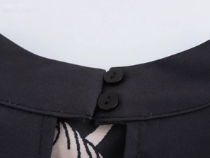 Close-up of neckline with buttons and beige vintage pattern on black fabric