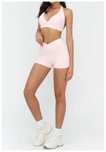 Detail of light pink yoga set featuring a halter V-neck top and cross high-waisted shorts