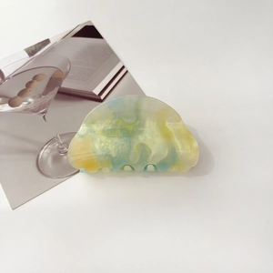 Detailed close-up of blue and yellow gradient cloud hair claw with subtle glitter