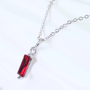 Close-up of silver necklace with rectangular red zircon pendant on a white background