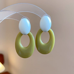 Macro view of vintage bicolor acrylic oval earrings in white and olive green resin