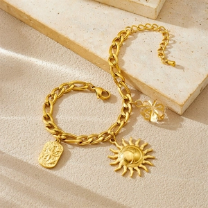 Golden chain bracelet set with sun and rectangle pendants on textured stone background
