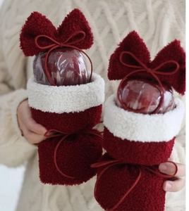 Close-up of lamb wool Christmas gift bags with red bows holding festive apples