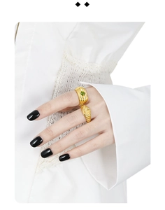 Detail of vintage gold-layered rings with green gemstone on model with lace sleeve
