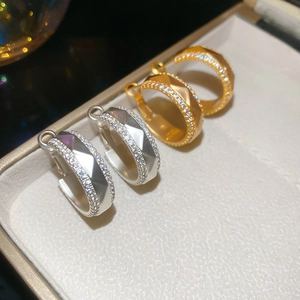 Dettaglio di orecchini a cerchio in oro e argento con zirconi su vassoio gioielli