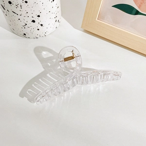 Detail of a large transparent square hair claw with golden spring and multi-tooth design