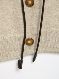 Close-up of knit jacket detail featuring marble-patterned buttons and brown drawstrings