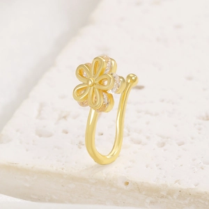 Macro detail of U-shaped non-pierced gold flower nose ring with sparkling zircon stones