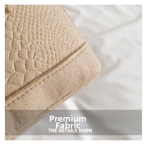 Detail shot of the embossed crocodile pattern and stitching on a beige shell bag