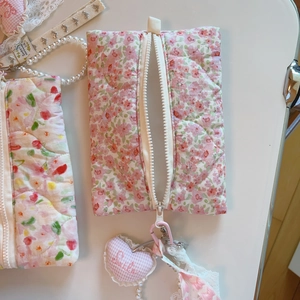 Détail de la pochette matelassée à fleurs roses avec breloque coeur et dentelle élégante