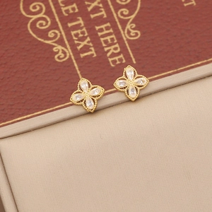 Detailed macro view of gold-plated four-petal flower earrings with white crystals
