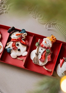 Close-up of resin snowman ornaments with plaid scarves in a red gift box display