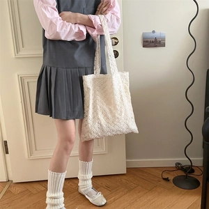 Close-up of white lace mesh tote bag featuring delicate floral patterns and shoulder strap