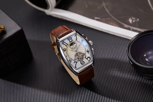 Detail of tonneau mechanical watch with blue numerals, moon phase, and brown leather strap